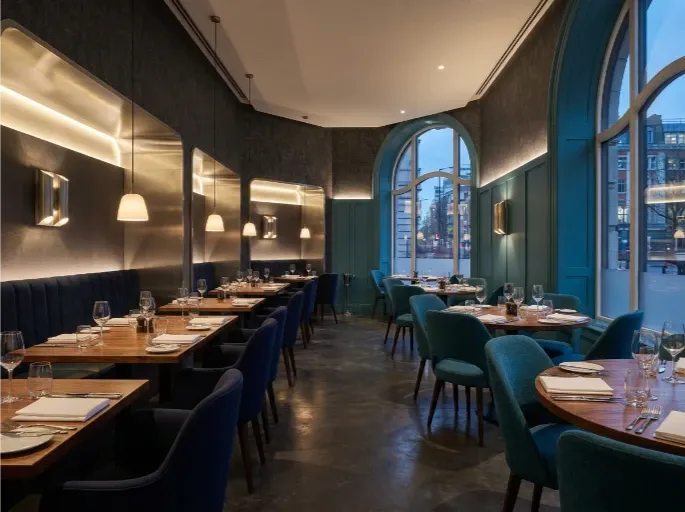 A stylish restaurant dining room with set tables and large arched windows