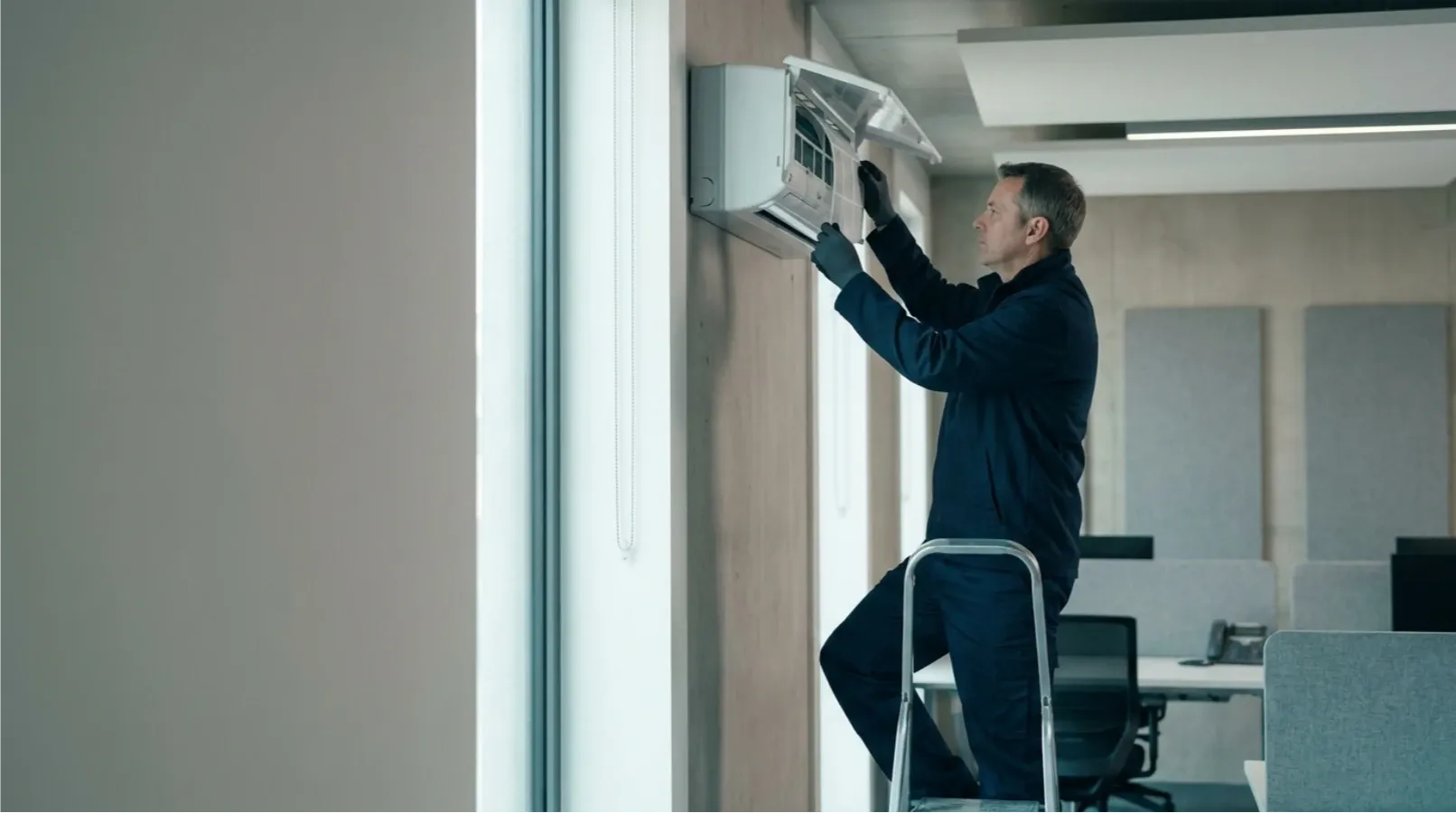A technician servicing a wall-mounted air-conditioning unit