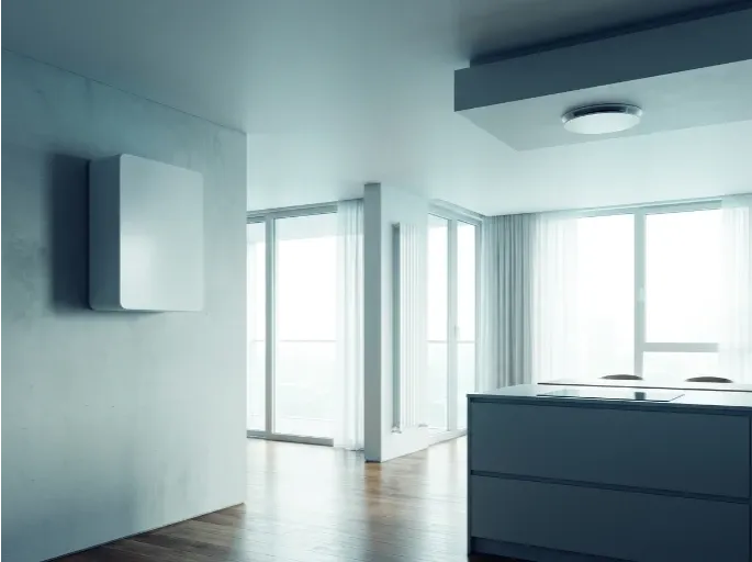 A wall-mounted domestic ventilation unit in a bright, modern open-plan living space